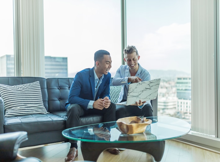 two men in suit sitting on sofa