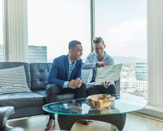 two men in suit sitting on sofa