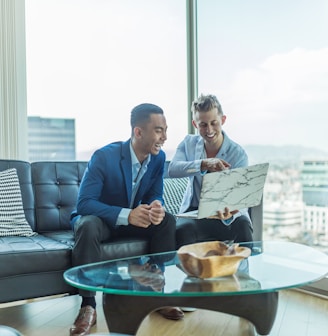 two men in suit sitting on sofa