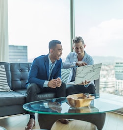 two men in suit sitting on sofa