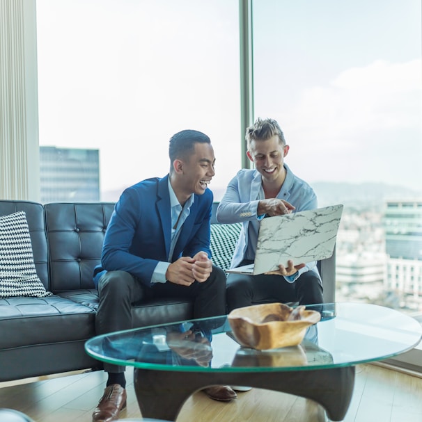 two men in suit sitting on sofa