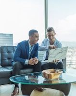 two men in suit sitting on sofa