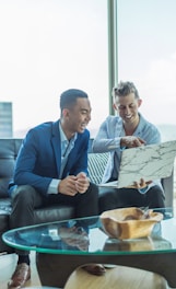 two men in suit sitting on sofa