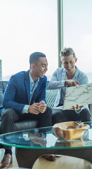 two men in suit sitting on sofa