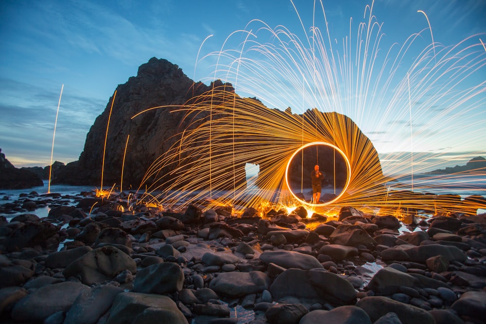 person standing on seashore steel wool photography