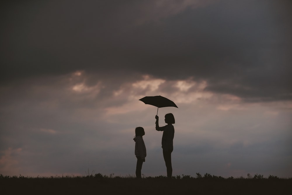 ragazza che tiene l'ombrello sul campo di erba