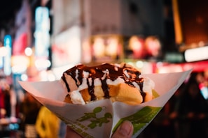 A smiling child holding a Nutella waffle with clouds and golden stars subtly visible in the background