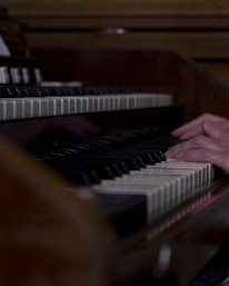 Close-up of hands playing a piano keyboard in a cozy studio.
