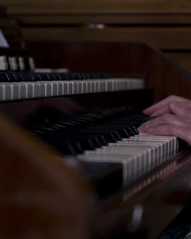 A close-up of hands gracefully playing gospel piano keys in a warmly lit church setting.