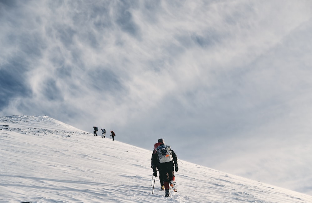 men climbing snow covered mountain