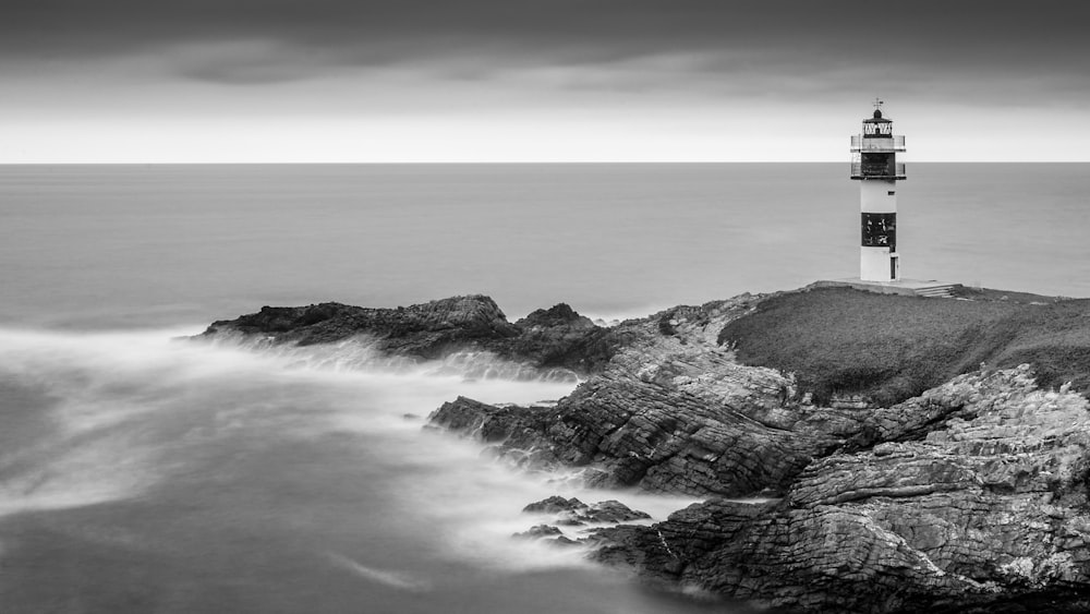 photo of lighthouse on cliff near body of water