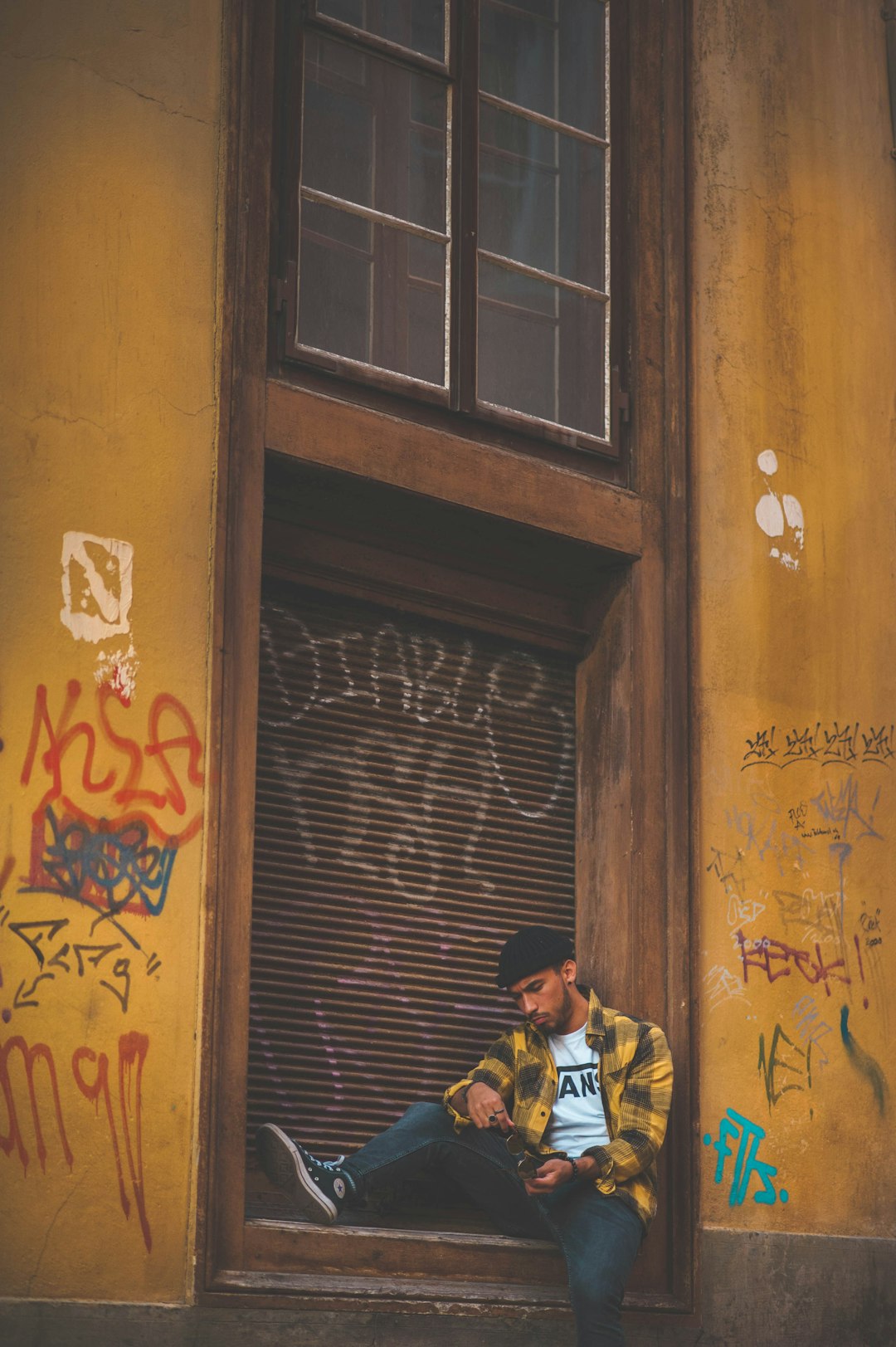 man sitting beside shutter gate