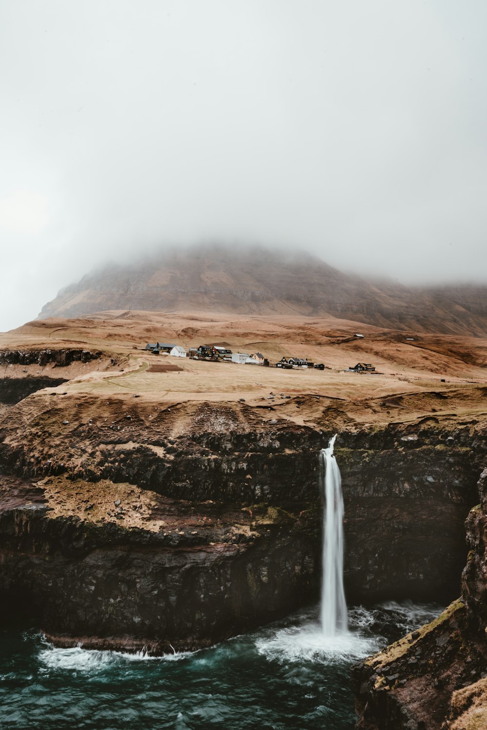 brown mountain with waterfalls under gray cloudy sky