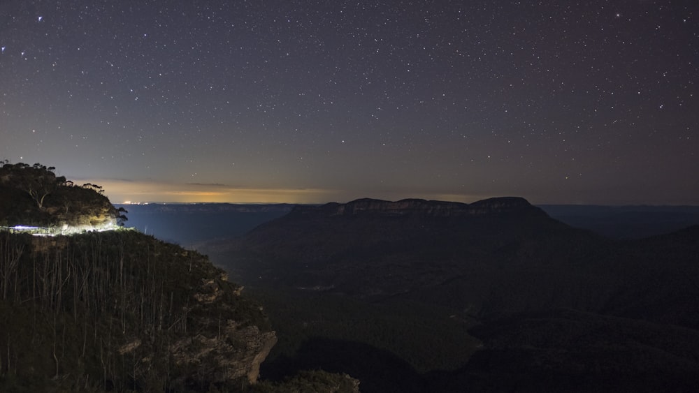 a view of a mountain at night with stars in the sky