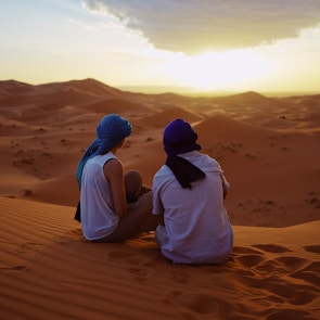 two men sitting on sand dunes