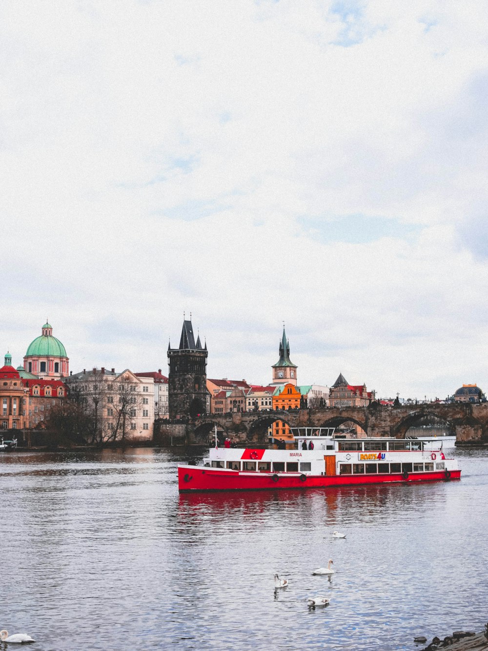 red and white boat in front of white and brown concrete buildings