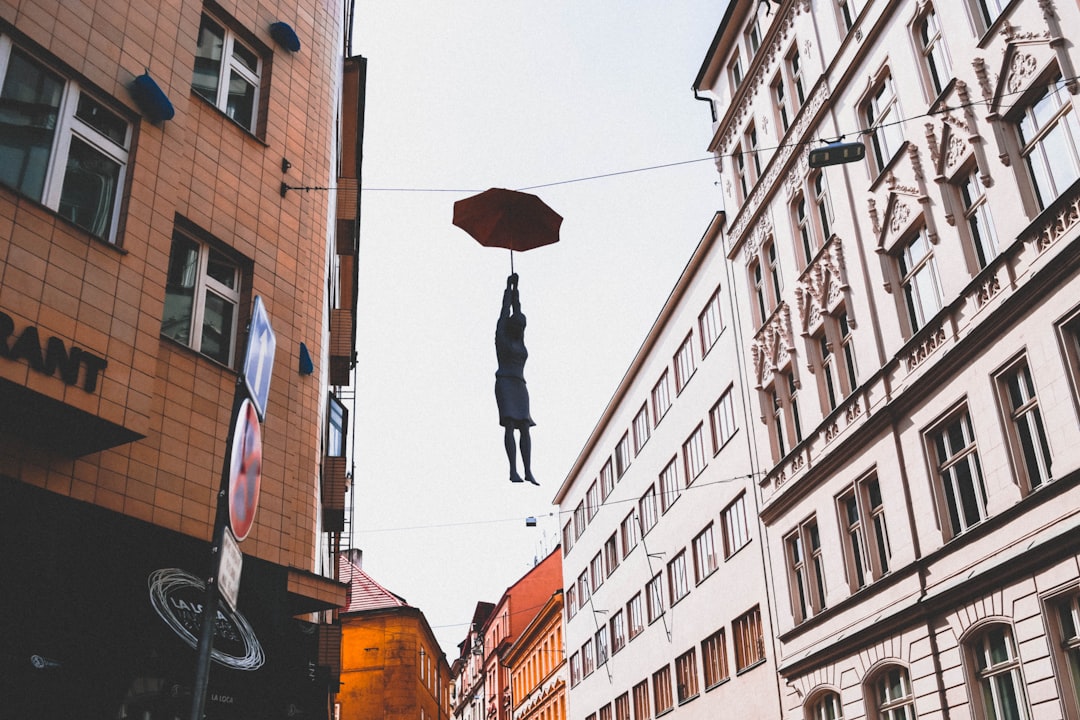 woman hanged on wire while holding umbrella between buildings at daytime