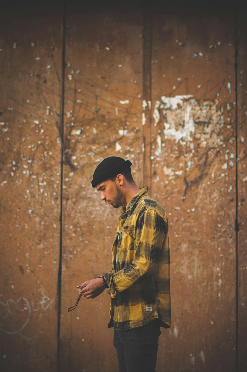 man wearing yellow and black plaid button-up long-sleeved shirt, black jeans and black knit cap