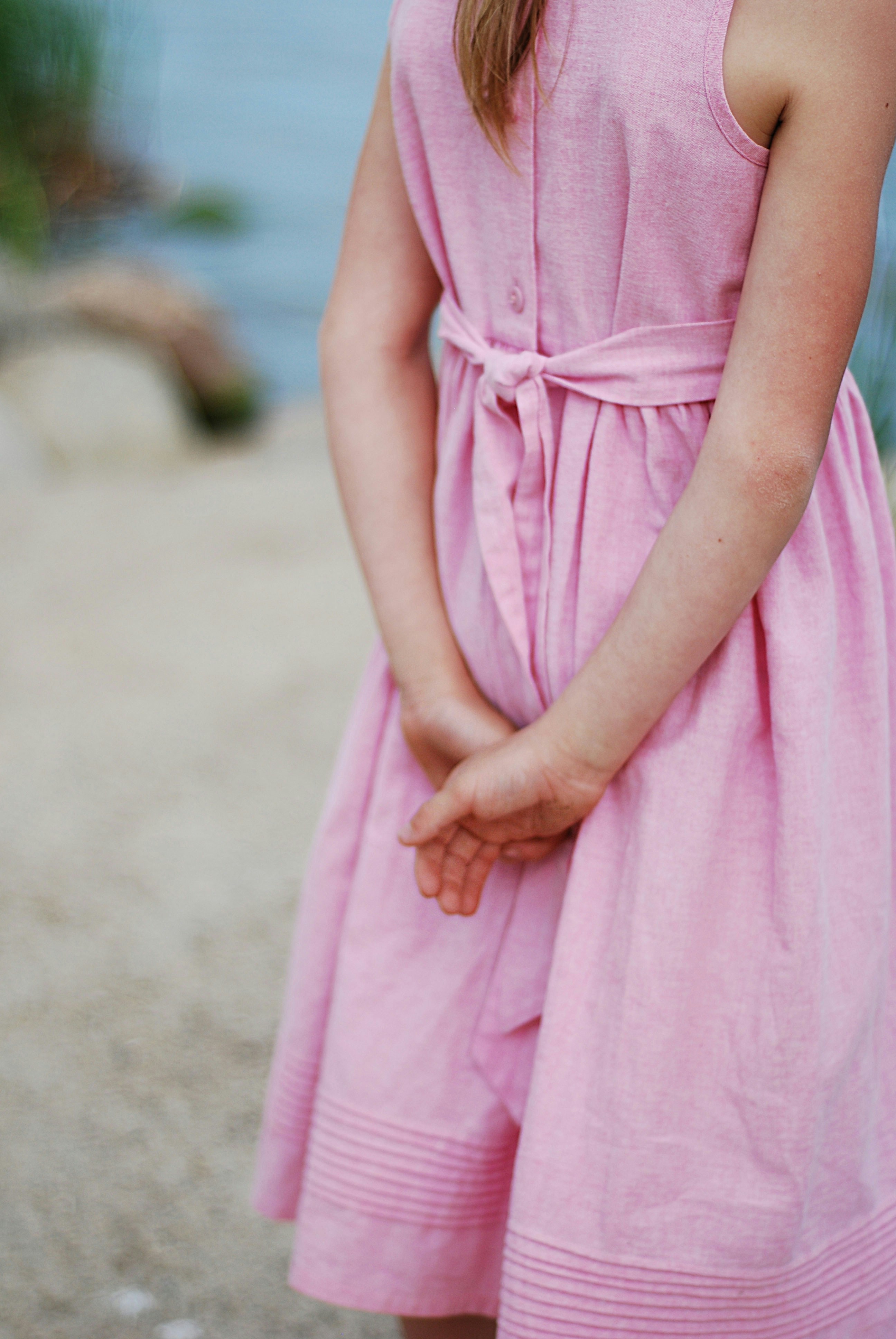 A Girl in a Pink Dress Doing the Clasped Arms Gesture