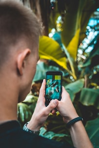 A person taking a photo with a smartphone in natural light outdoors.