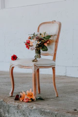 Close-up of a delicate bouquet resting on a beige velvet armchair in the room.