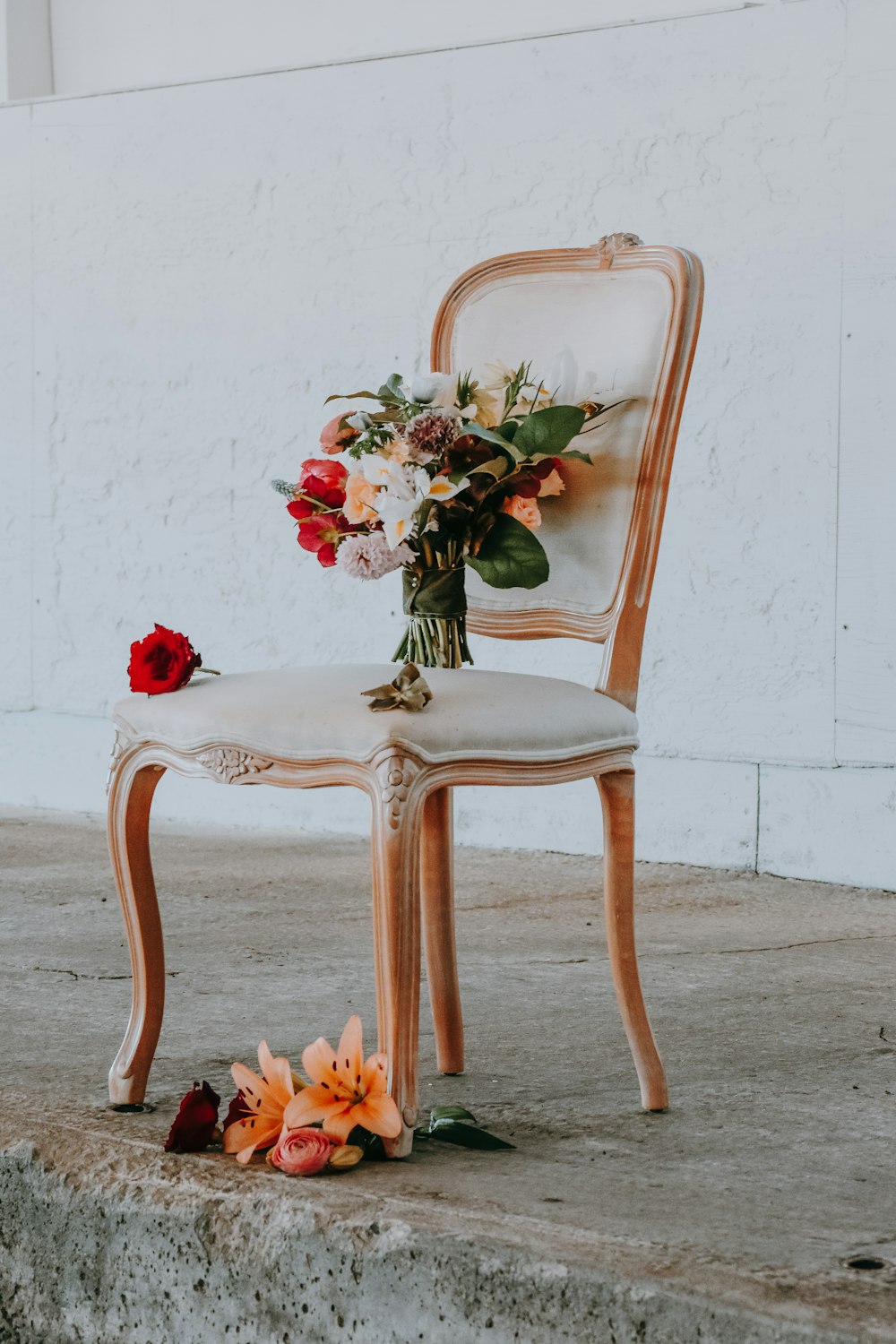 fleurs de couleurs assorties sur une chaise rembourrée beige encadrée en bois brun près du mur