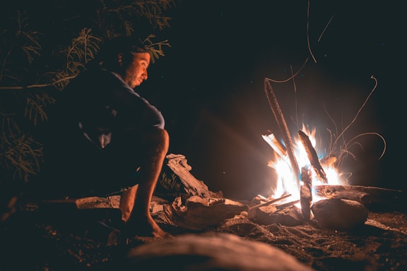 man seating beside fire