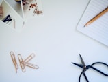 photo of black scissors beside notebook and pencil