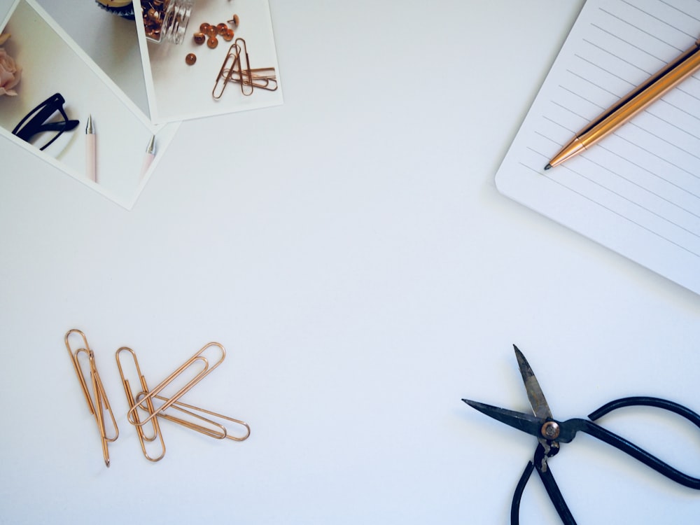 photo of black scissors beside notebook and pencil