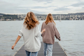 two women standing on dock front of sea at daytime