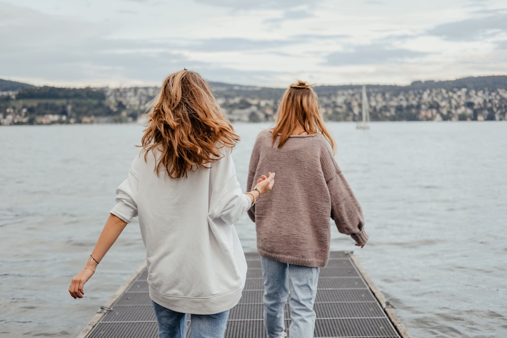 Zwei Frauen stehen tagsüber auf dem Dock vor dem Meer