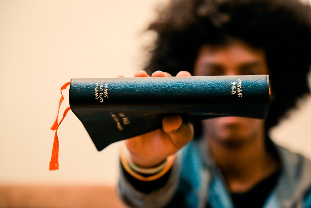 selective focus photography of man holding Holy Bible