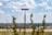 A blue road sign that reads 'Seminary Drive' is mounted on a wooden post. The background reveals a vast landscape with green fields and a distant view of houses under a partly cloudy sky. Some out-of-focus plants appear in the foreground.