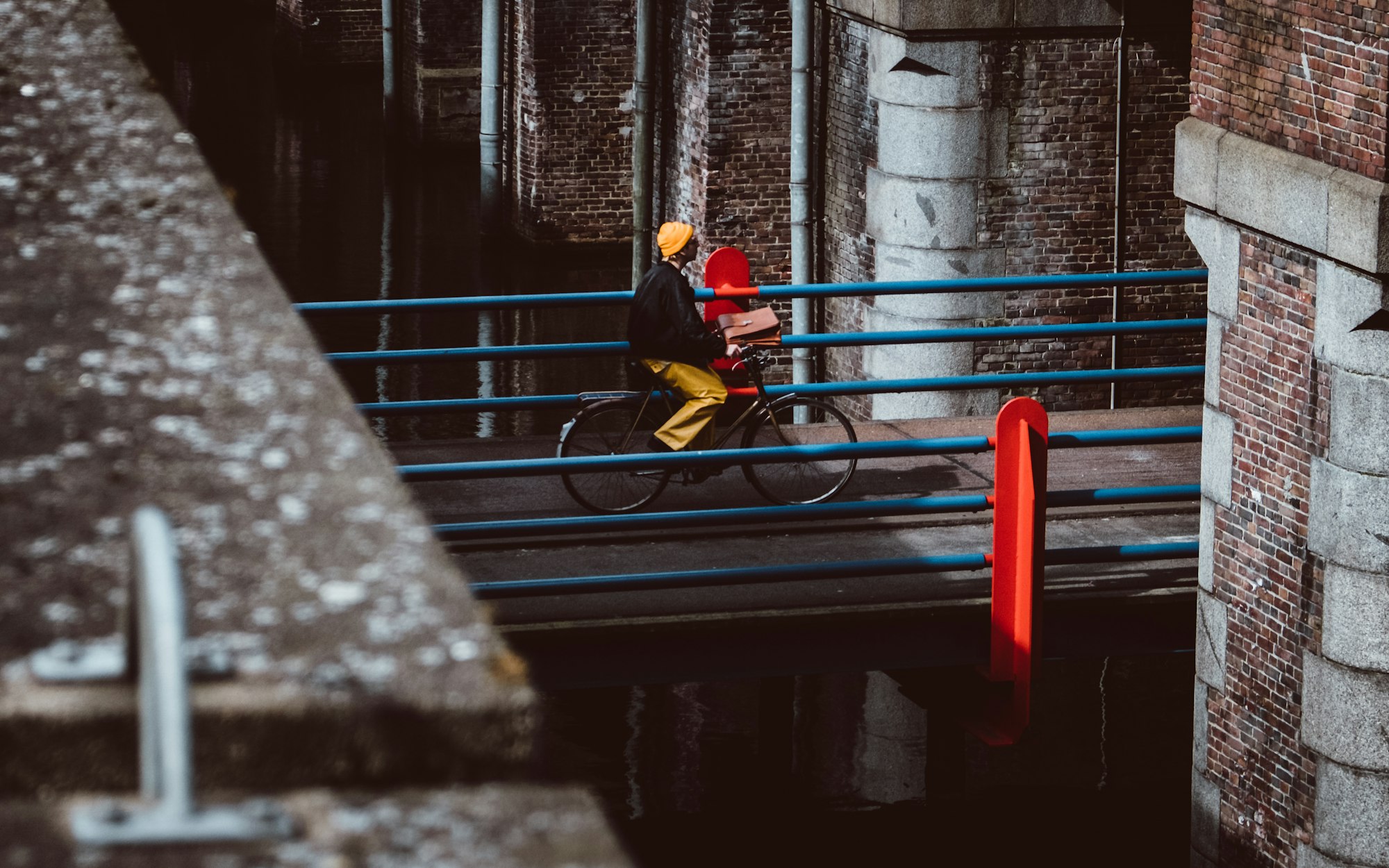 This guy was really standing out with his yellow jeans and orange beanie. I also like the contrast with the blue and red bridge. Took this in Amsterdam a while ago.