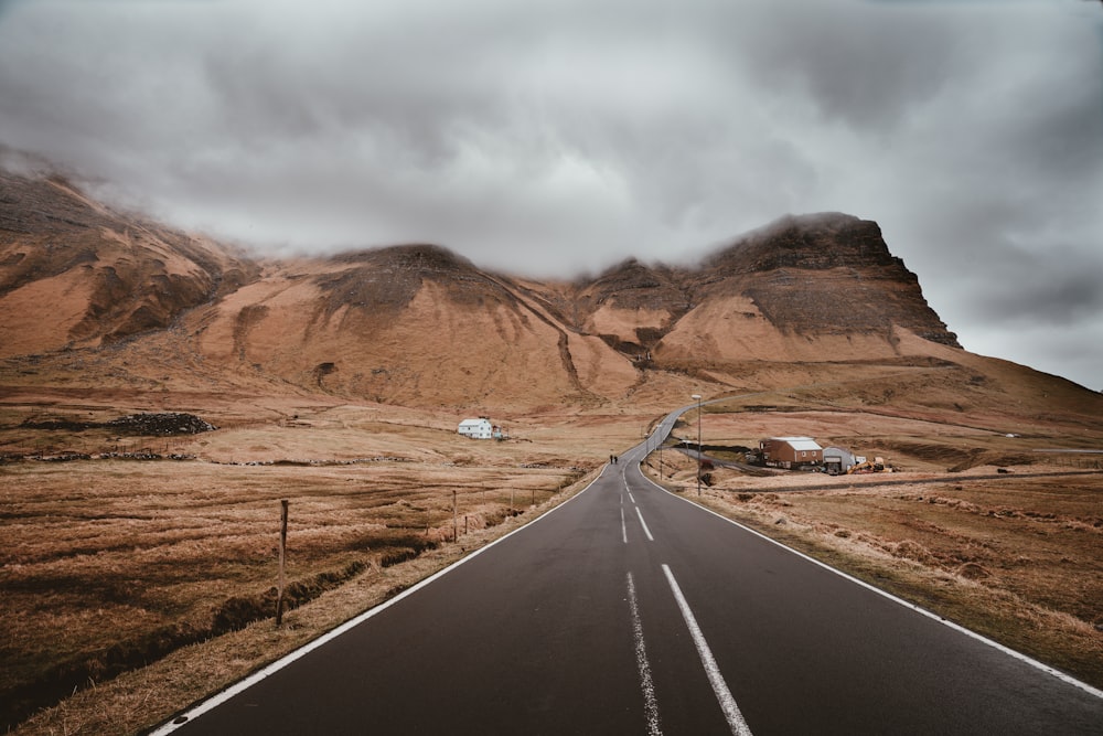 road in the middle of brown field during black clouds