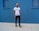 A person stands against a vivid blue wall, wearing a pink cap, white t-shirt with the word 'YOUTH' in colorful letters, black ripped jeans, and sneakers. The setting appears to be urban with a minimalist and stylish vibe.
