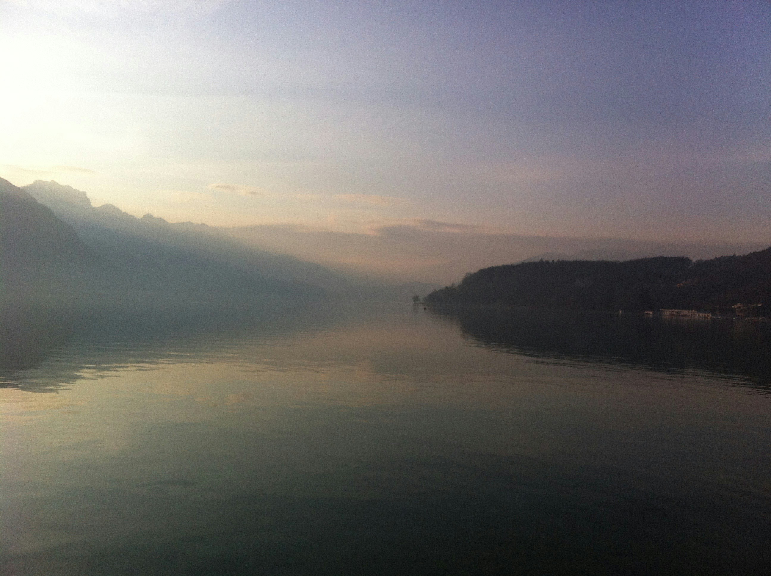 Mountain lake at sunrise with mist rising from calm blue water