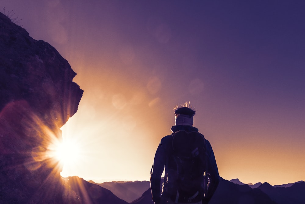 silhouette photography of standing person near boulder