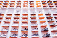 Sneaker collection arranged neatly on a trendy rack with splashes of blue and orange accents.