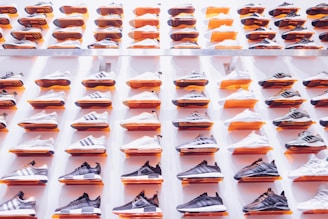 A stylish arrangement of name brand sneakers, cologne bottles, and apparel neatly displayed on a cozy wooden table.