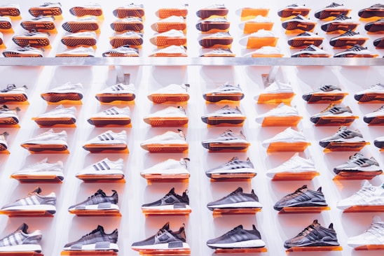 A stylish arrangement of name brand sneakers, cologne bottles, and apparel neatly displayed on a cozy wooden table.