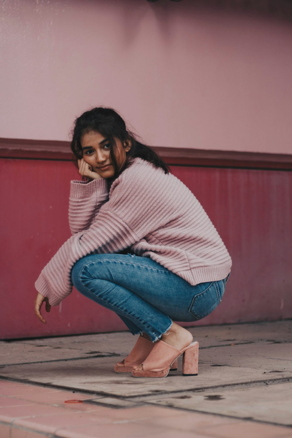 Fotografía de mujer en suéter rosa y pantalones vaqueros azules atraquetándose