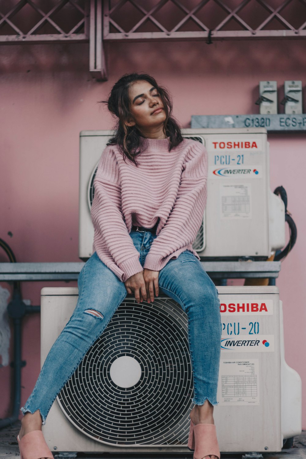 woman sitting near Toshiba air condenser