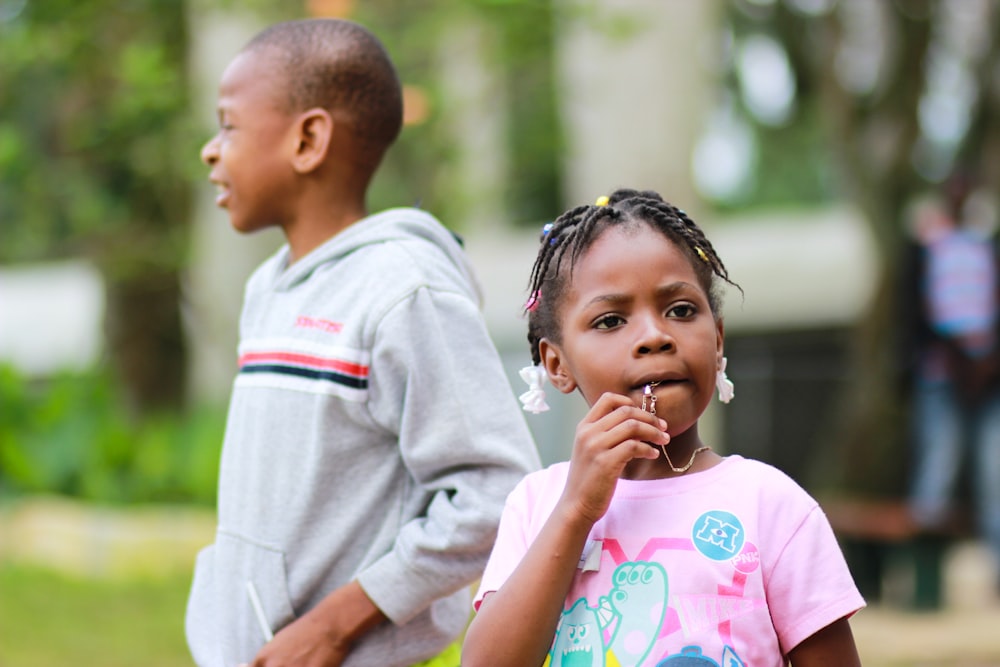 selective focus photography of girl biting her pendant beside a boy in gray pullover hoodie