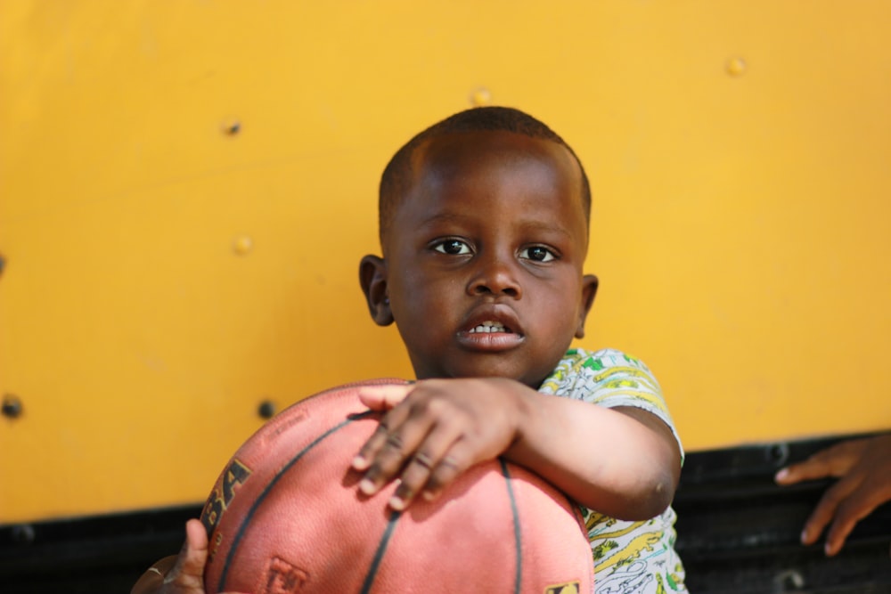 Niño sosteniendo una pelota de baloncesto marrón