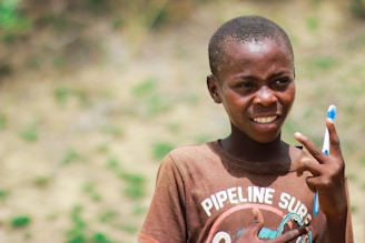 A smiling child holding a toothbrush with a playful expression.