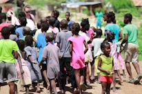 Volunteers and children participating in an outdoor socioeducational activity under bright sunlight.