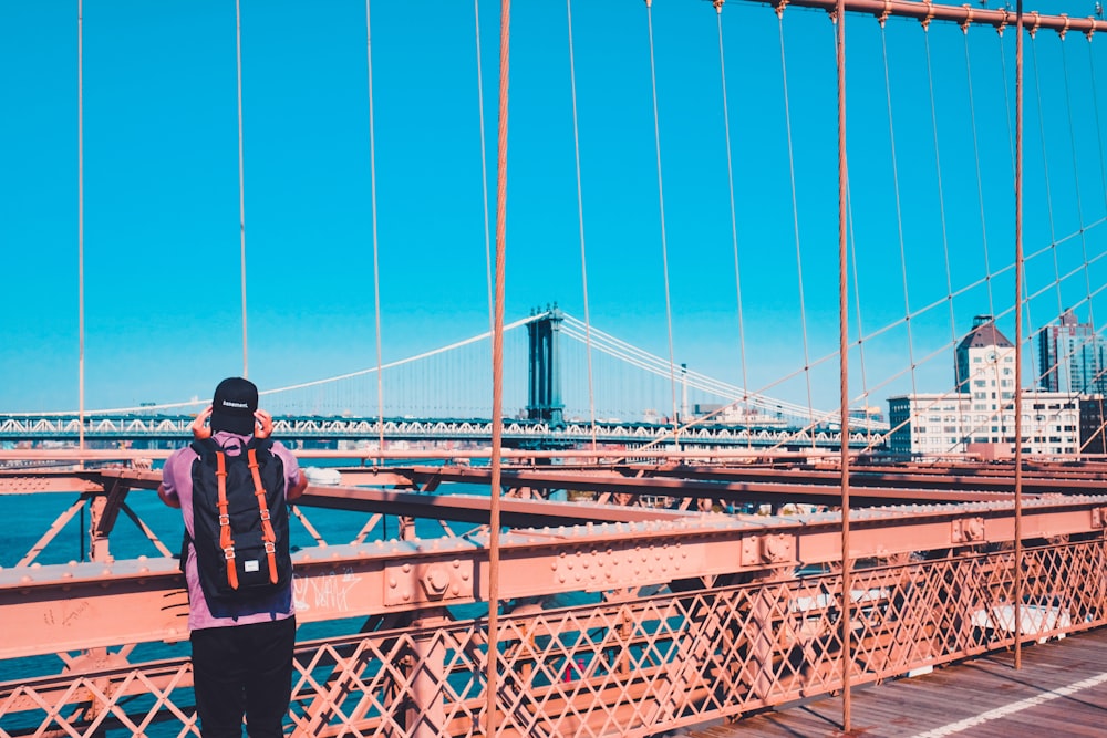 Mann steht tagsüber auf der Brooklyn Bridge mit Blick auf die Manhattan Bridge