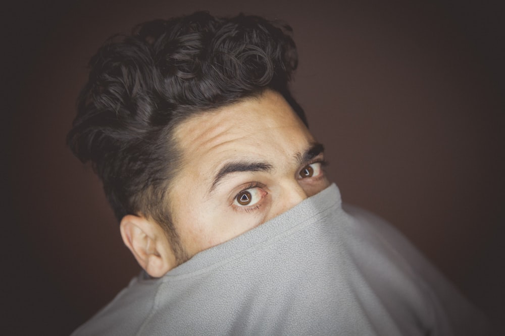 man covering his face with his crew-neck top