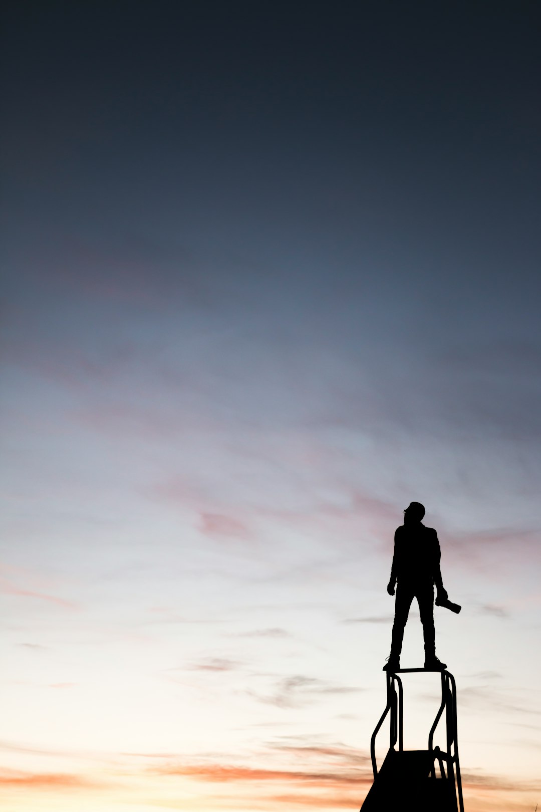 silhouette of man standing on slide while holding camera